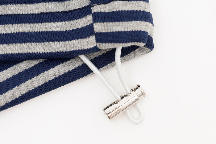 Close-up of a white drawstring threaded through striped fabric with a shiny metal cord lock