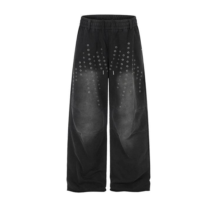 Washed black wide-leg sweatpants with scattered metal eyelet grommet detail on front thighs, elastic waistband, straight cut