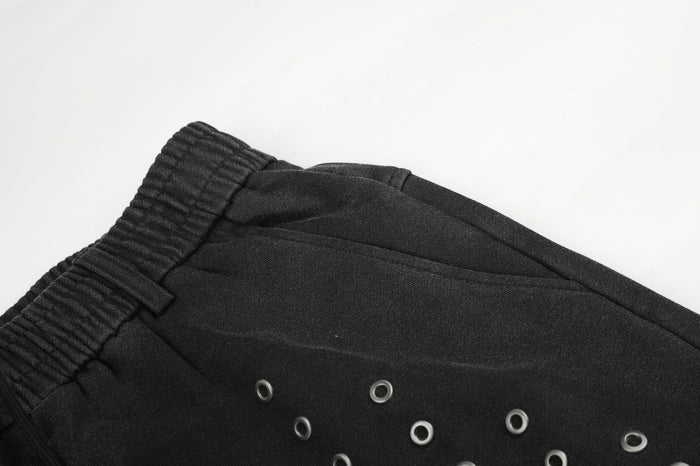 Close-up of the elastic black waistband, belt loop, upper seam, and silver eyelets on the front panel
