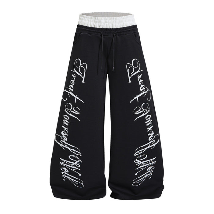 Front view of black wide-leg sweatpants with a white contrast waistband, drawstring, and white cursive leg prints