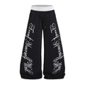 Front view of black wide-leg sweatpants with a white contrast waistband, drawstring, and white cursive leg prints