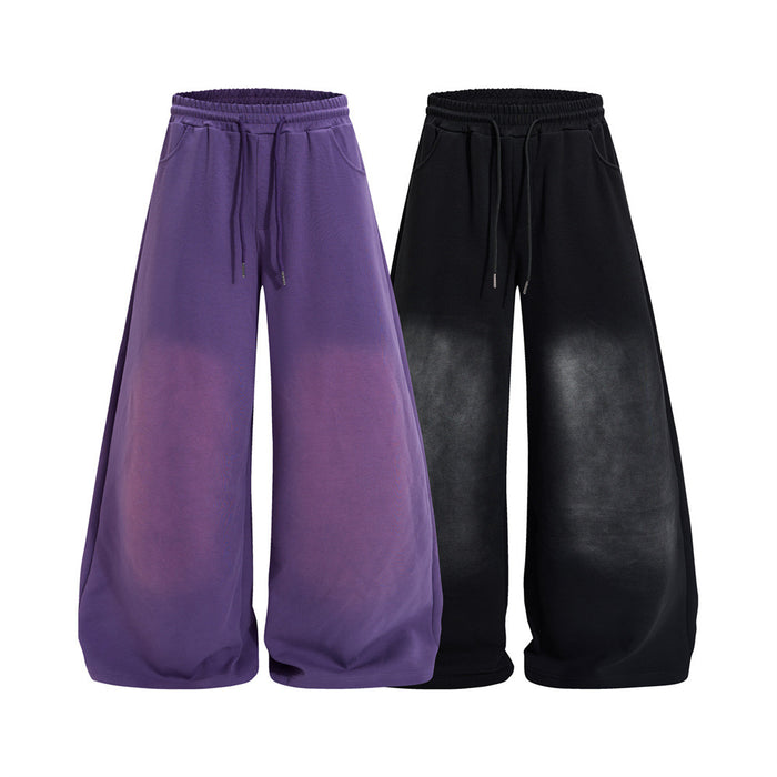 Wide-leg sweatpants shown front-facing in purple and black with elastic waists, drawstrings, and faded leg panels