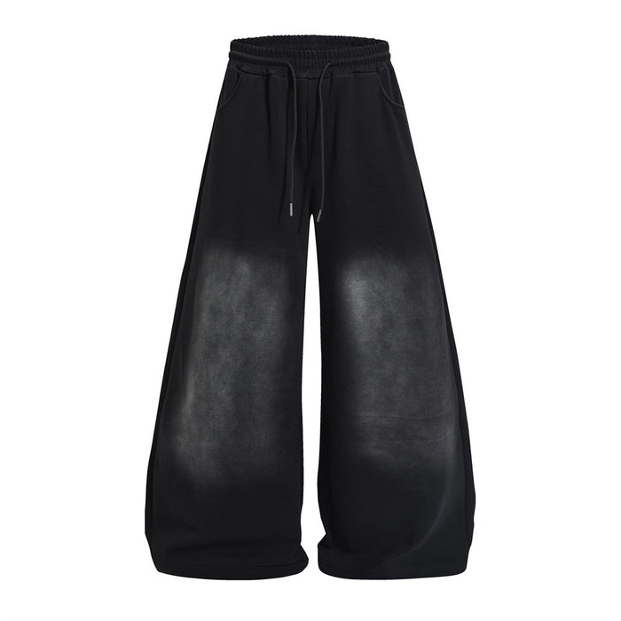 Black wide-leg sweatpants shown from the front with elastic waistband, drawstring, pockets, and faded leg panels