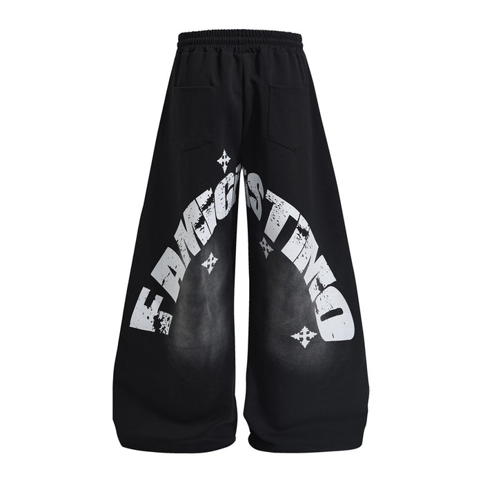 Black wide-leg sweatpants shown from the back with large distressed white arched lettering and star graphics