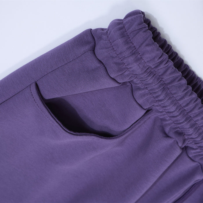 Close-up of a purple sweatpants side pocket and gathered elastic waistband stitching