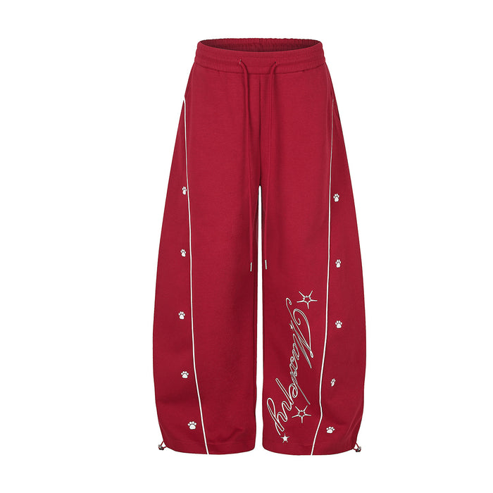 Red wide-leg sweatpants with contrast white piping, paw print graphics and cursive script hem detail, front and back view
