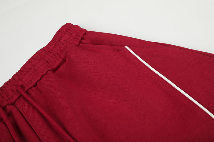 Close-up of the gathered elastic waistband and white contrast piping on red wide-leg sweatpants