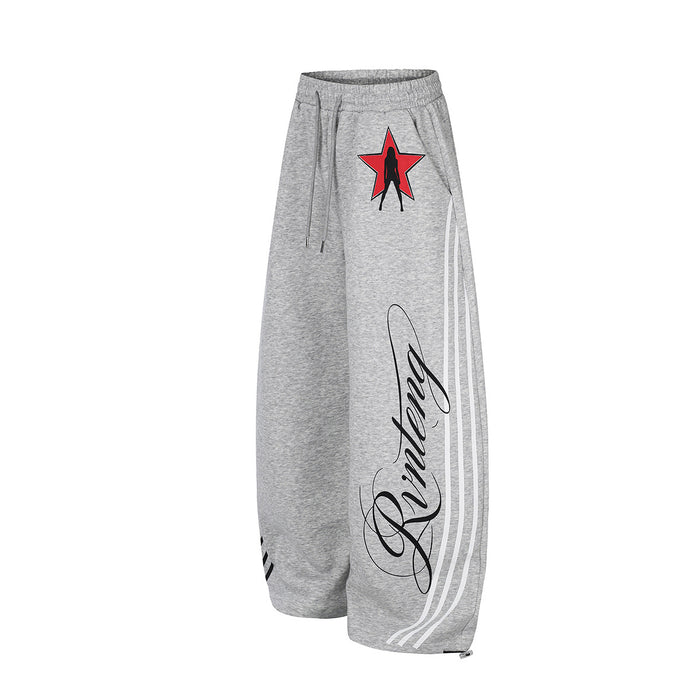Front three-quarter view of heather gray wide-leg sweatpants with white side stripes, red star graphic, and script print