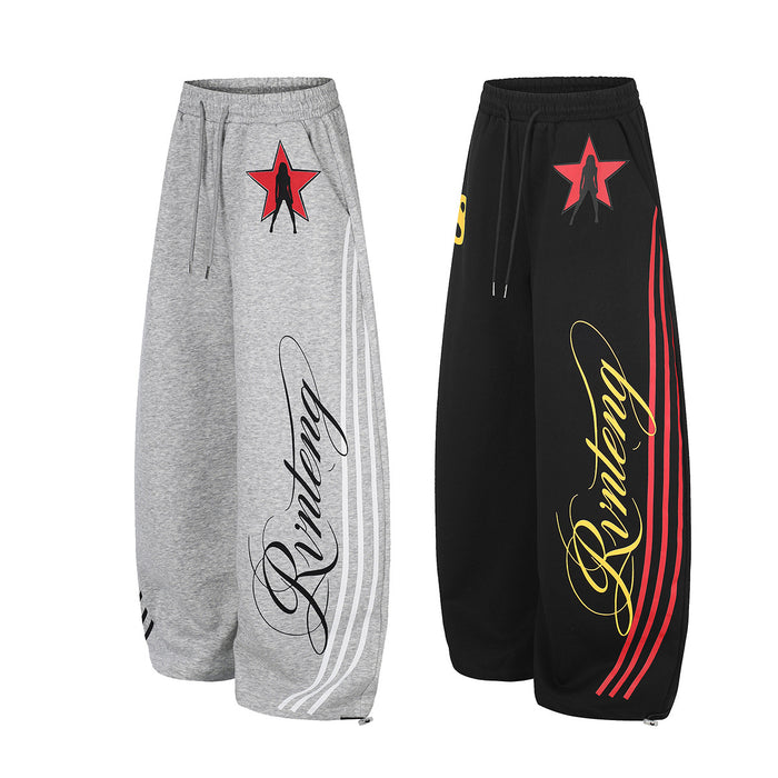 Front view of gray and black wide-leg sweatpants displaying matching star graphics, script prints, and striped legs