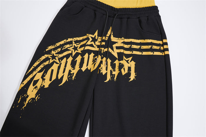 Close-up of black sweatpants showing the distressed yellow star graphic, drawstring, and front pockets