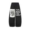Black wide-leg sweatpants with distressed unicorn appliqué patch and graffiti-style text print on the front leg, shown front