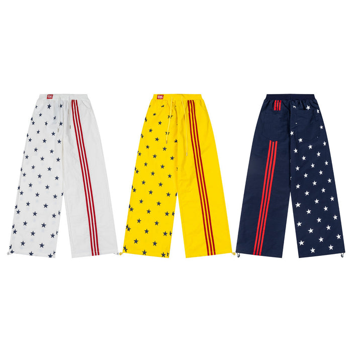 Three pairs of wide-leg track pants in white, yellow, and navy with star prints and red triple stripes