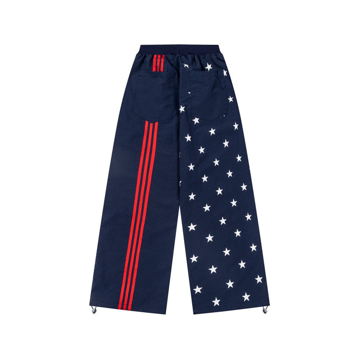 Reverse view of navy wide-leg track pants with white stars on one leg and red triple stripes on the other