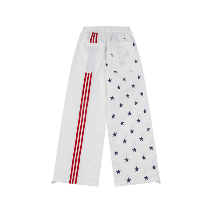 Reverse view of white wide-leg track pants with navy stars on one leg and red triple stripes on the other