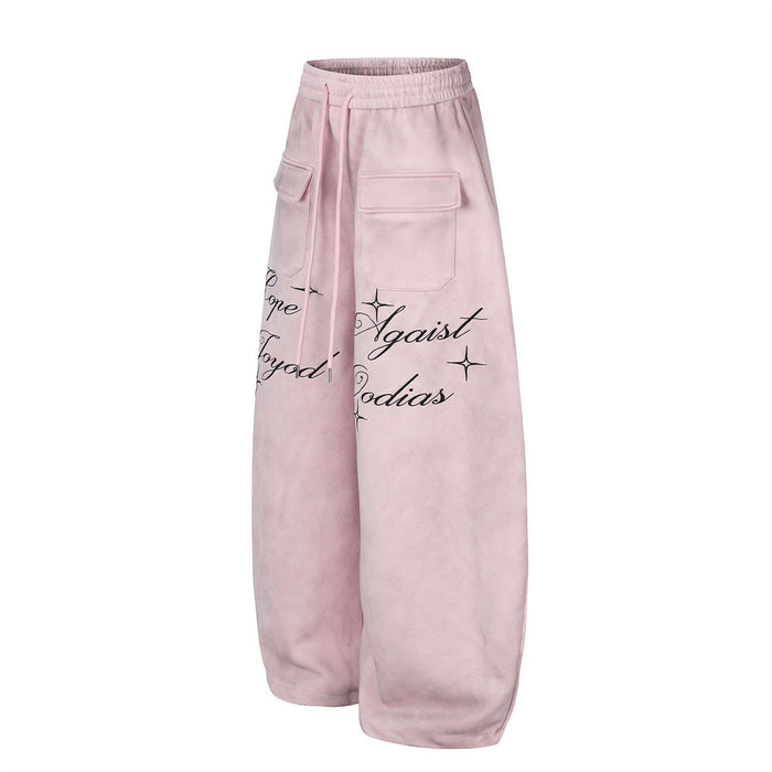 Angled side view of pink wide-leg velour sweatpants showing a cargo pocket and black script lettering