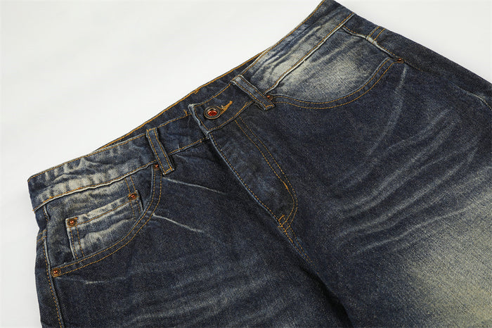 Close-up of the jeans front waist showing belt loops, button closure, curved pockets, and faded whiskering