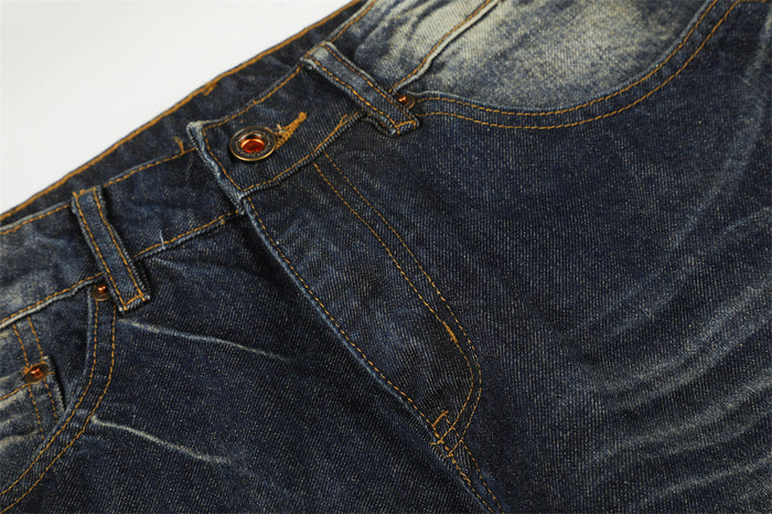 Detailed view of the denim waistband and button fly with golden stitching and pronounced front whiskering