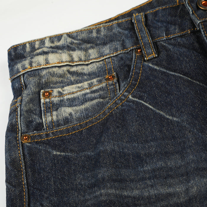 Close-up of the front coin pocket and curved pocket seam on faded dark blue denim