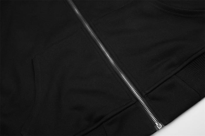 Close-up of the black hoodie front showing the silver zipper, kangaroo pocket edge, and ribbed hem