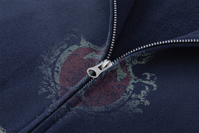 Detailed view of the silver zipper over the distressed red and gray crest on a navy hoodie