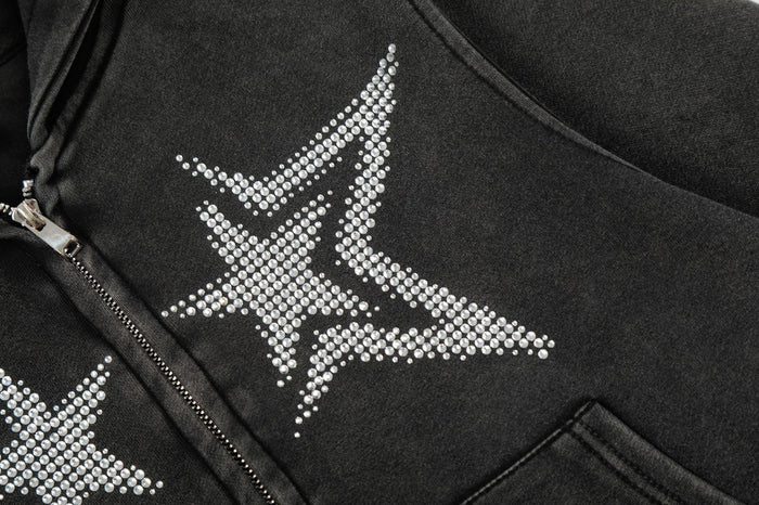Detailed close-up of a silver rhinestone star graphic beside the black hoodie zipper